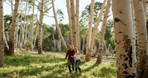 A couple pose in a forest in Flagstaff, one of the 5 best summer engagement session locations in Arizona