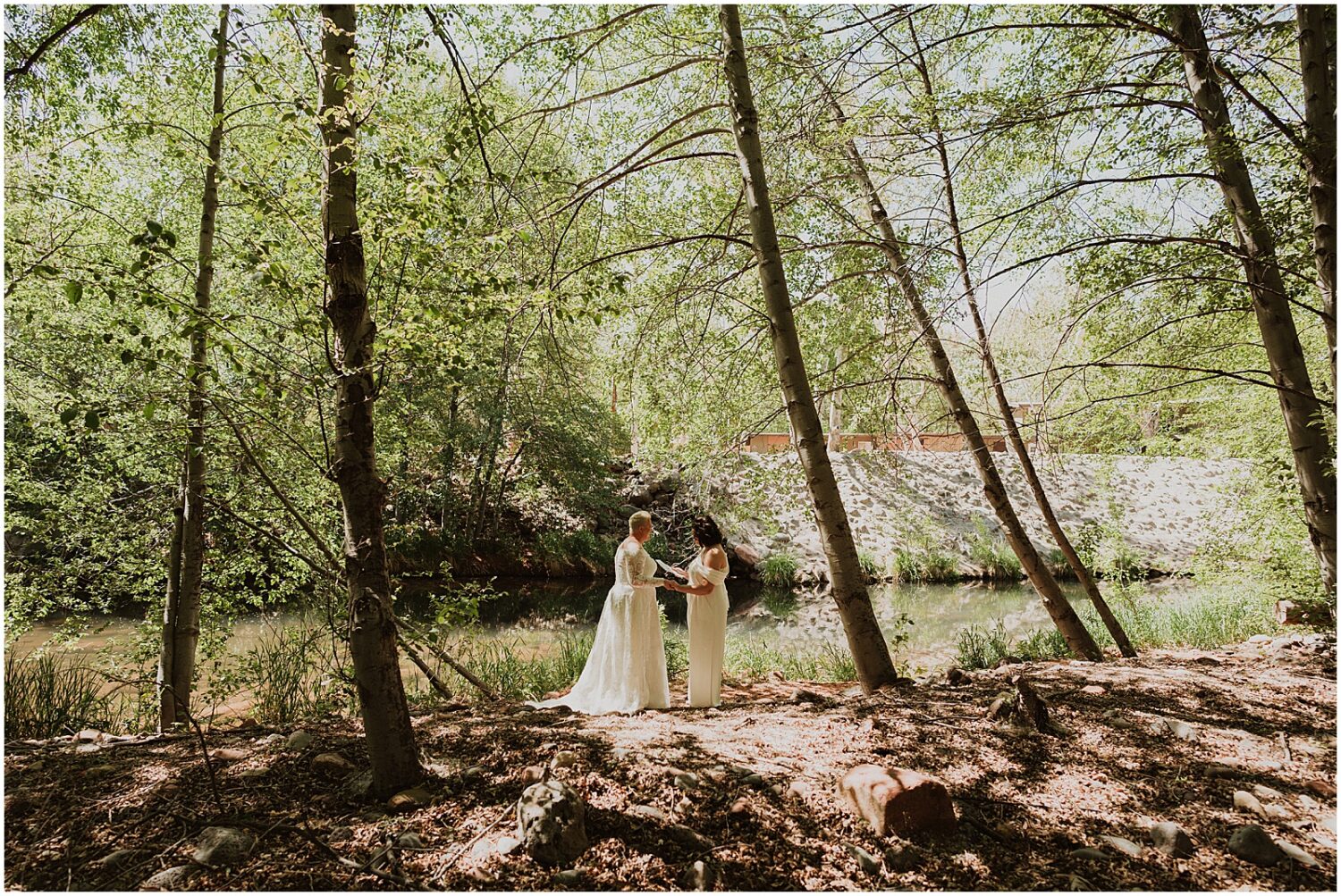 Two brides stand beside a creek exchanging private vows at Creekside Inn Sedona.