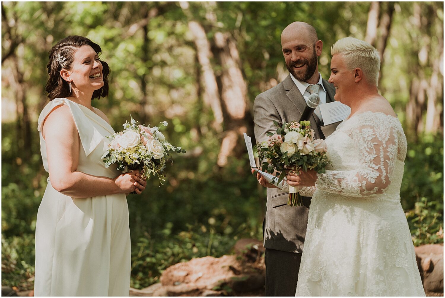 Two brides smile and hold bouquets during a wedding ceremony at Creekside Inn Sedona.