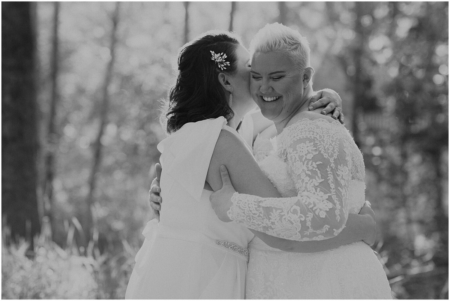 A bride kisses her bride on the cheek.