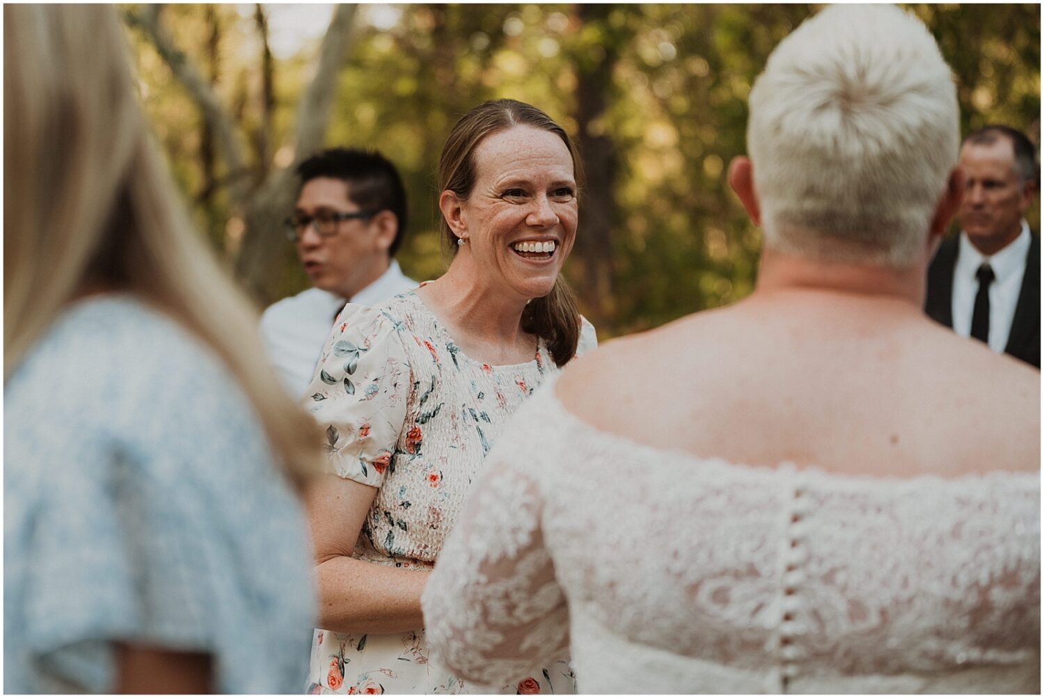 Wedding guests smile and talk with a bride.