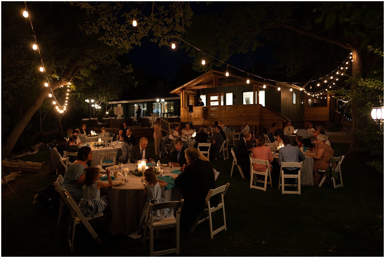 Wedding guests sit at candlelit tables.