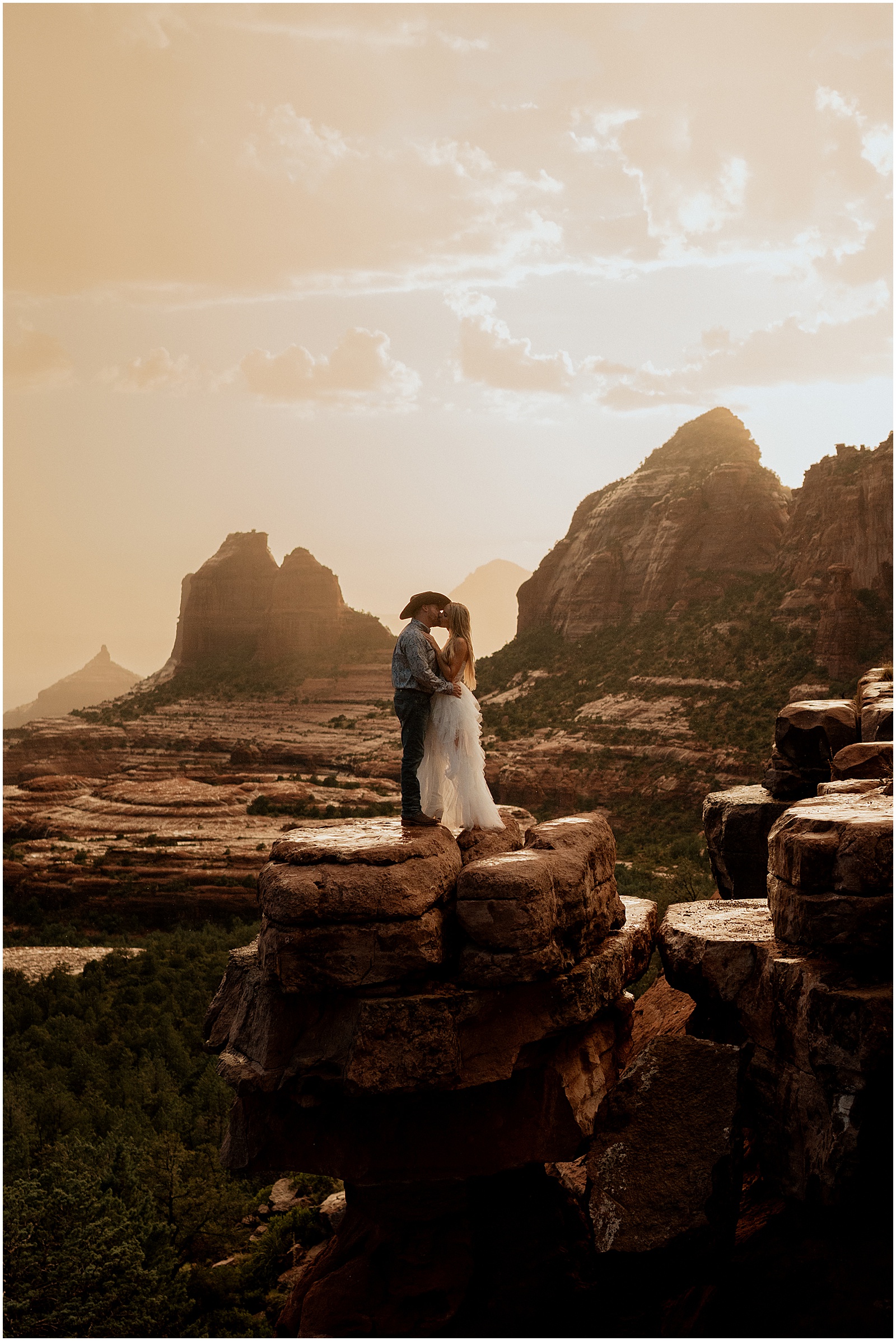 A man and woman kiss on Merry Go Round Rock in Sedona engagement photos.