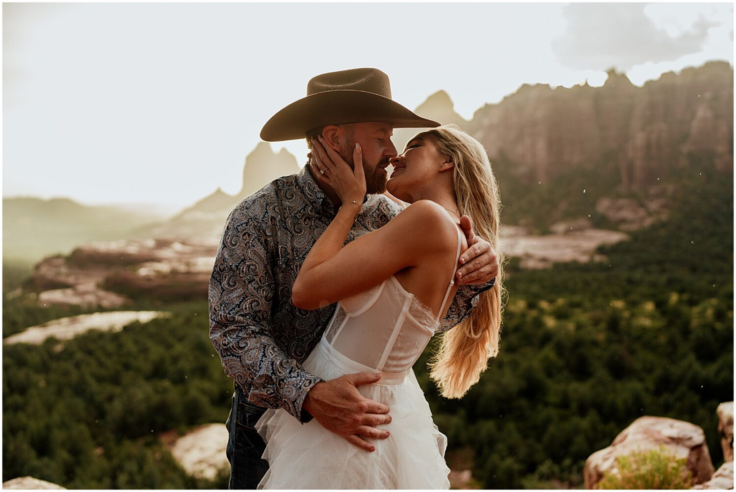 A man and woman kiss on a hiking trail in Sedona.