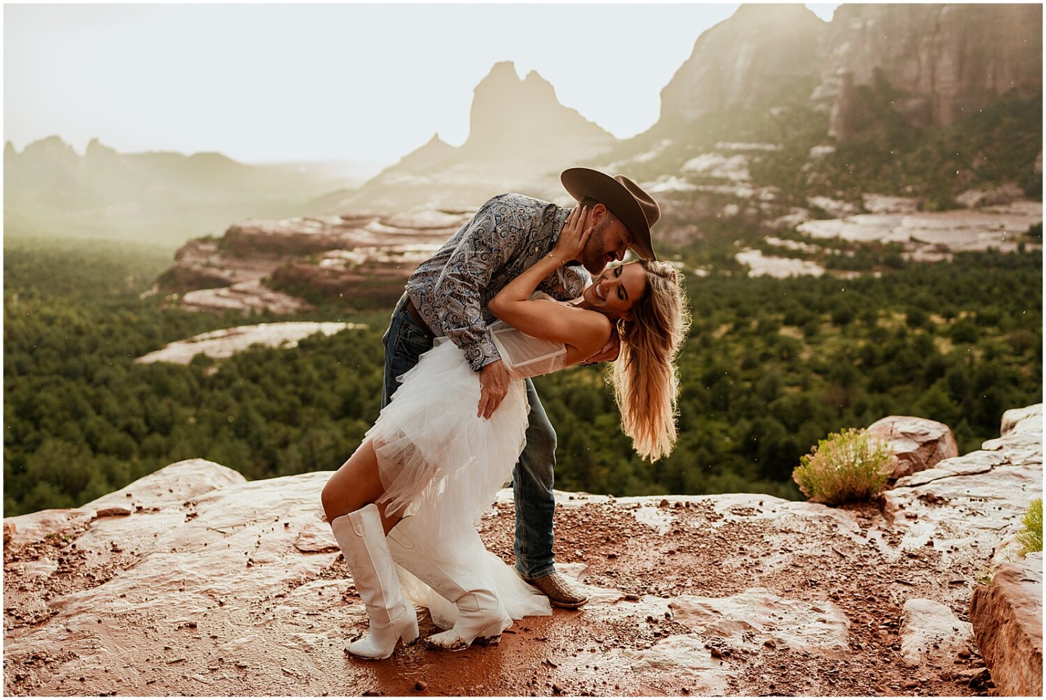 A man dips a woman for a kiss for Sedona engagement photos.