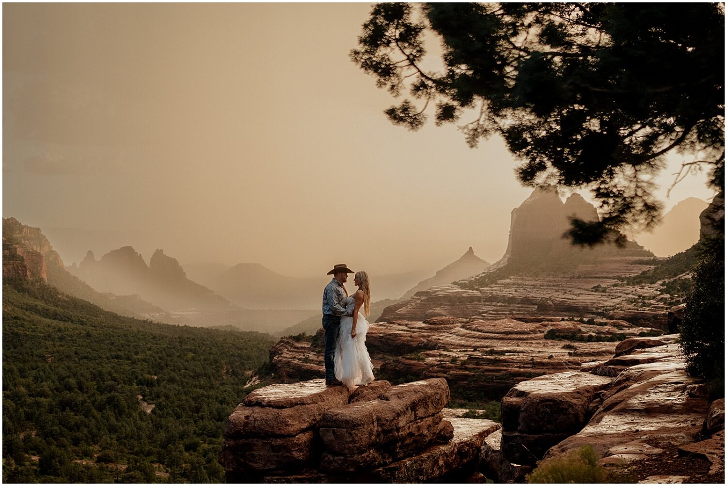 A man and woman hold hands at an outlook on a hiking trail.