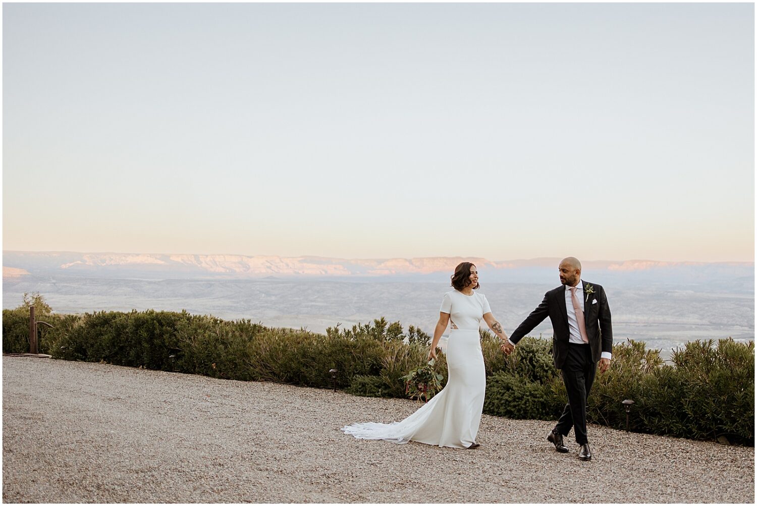 A bride and groom walk down a desert path in Jerome.