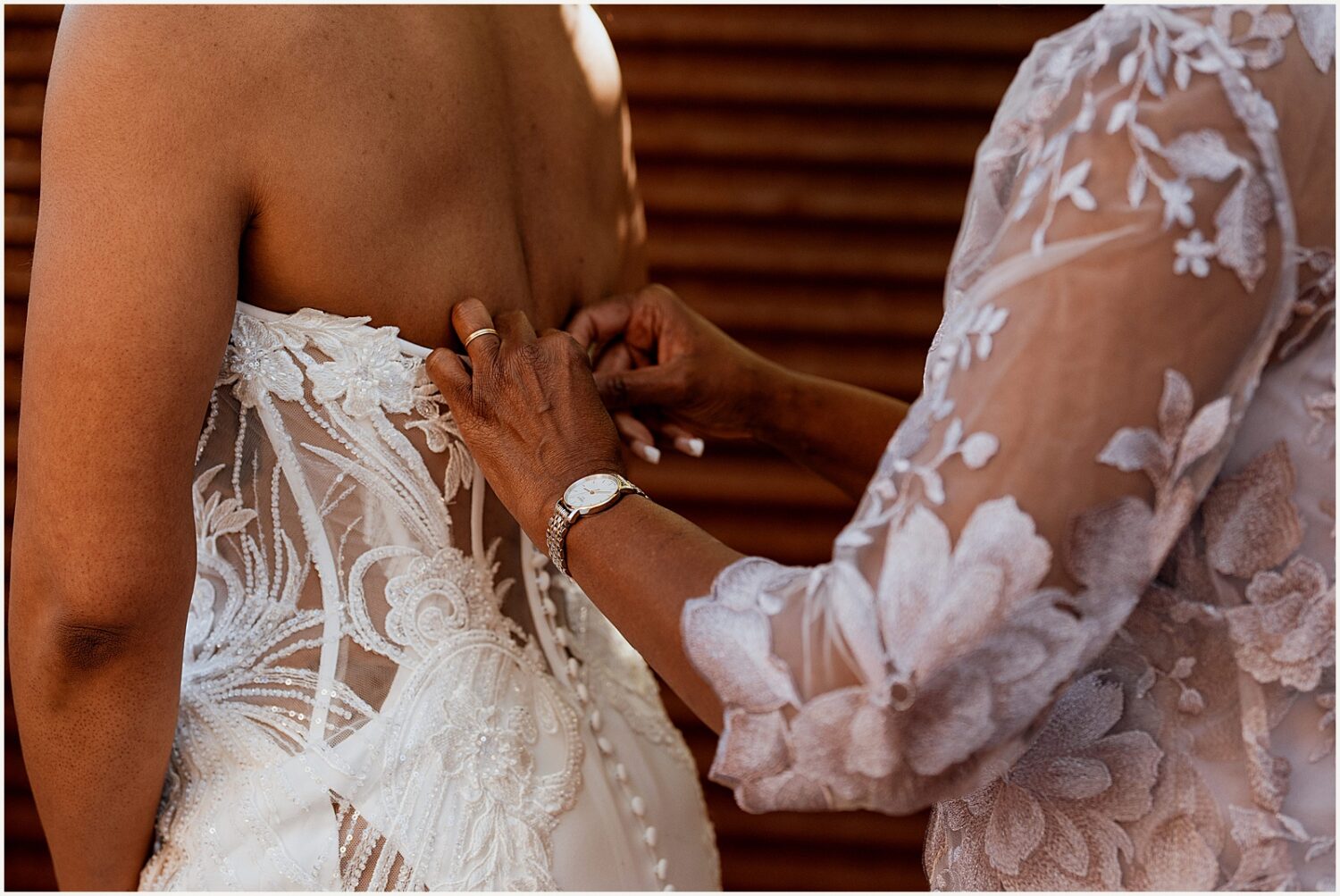 A bride's mother buttons her wedding dress.