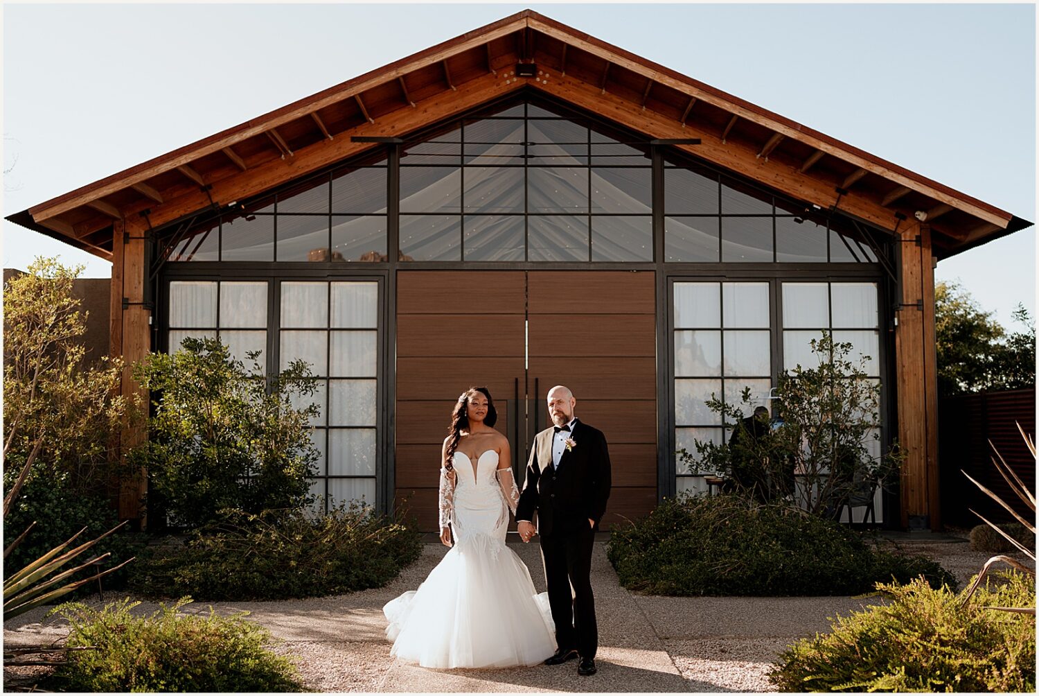 A bride and groom pose in front of an Apache Junction wedding venue.