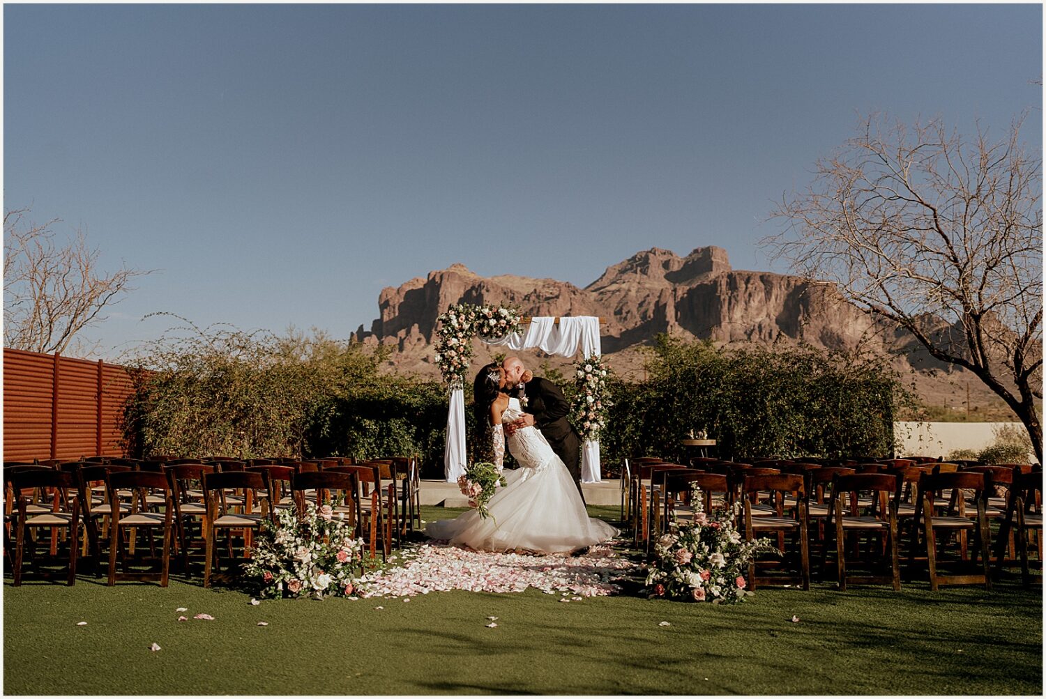 A bride and groom kiss at their ceremony site an Apache Junction wedding venue.