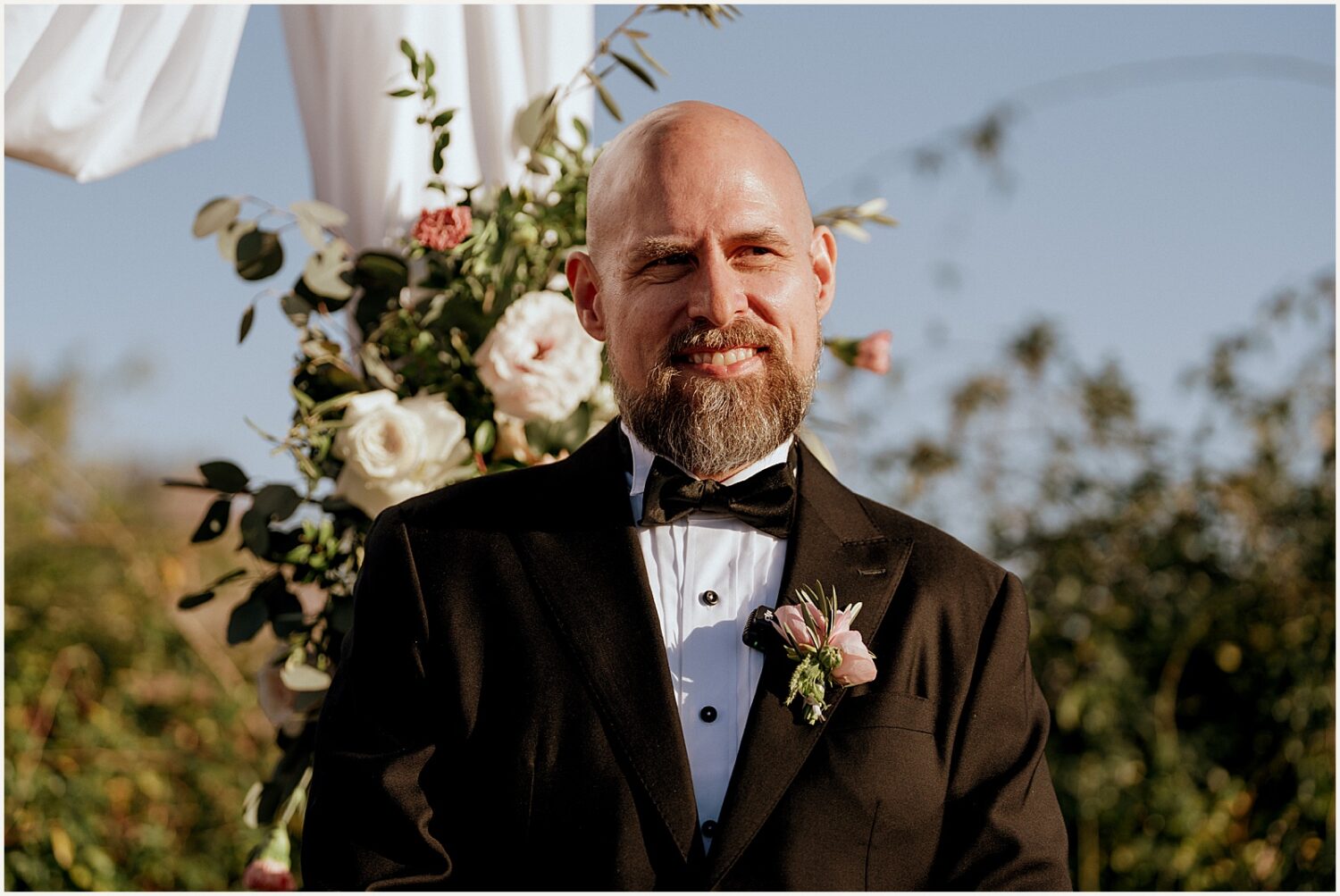 A groom smiles at the altar.