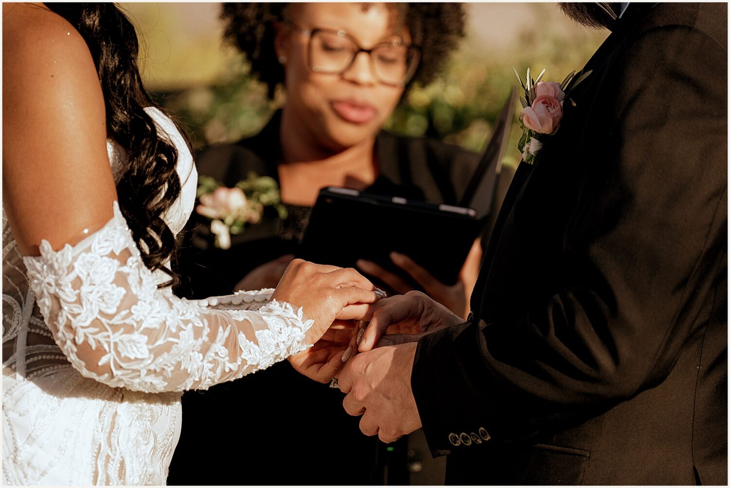 A bride puts a ring on a groom's finger.