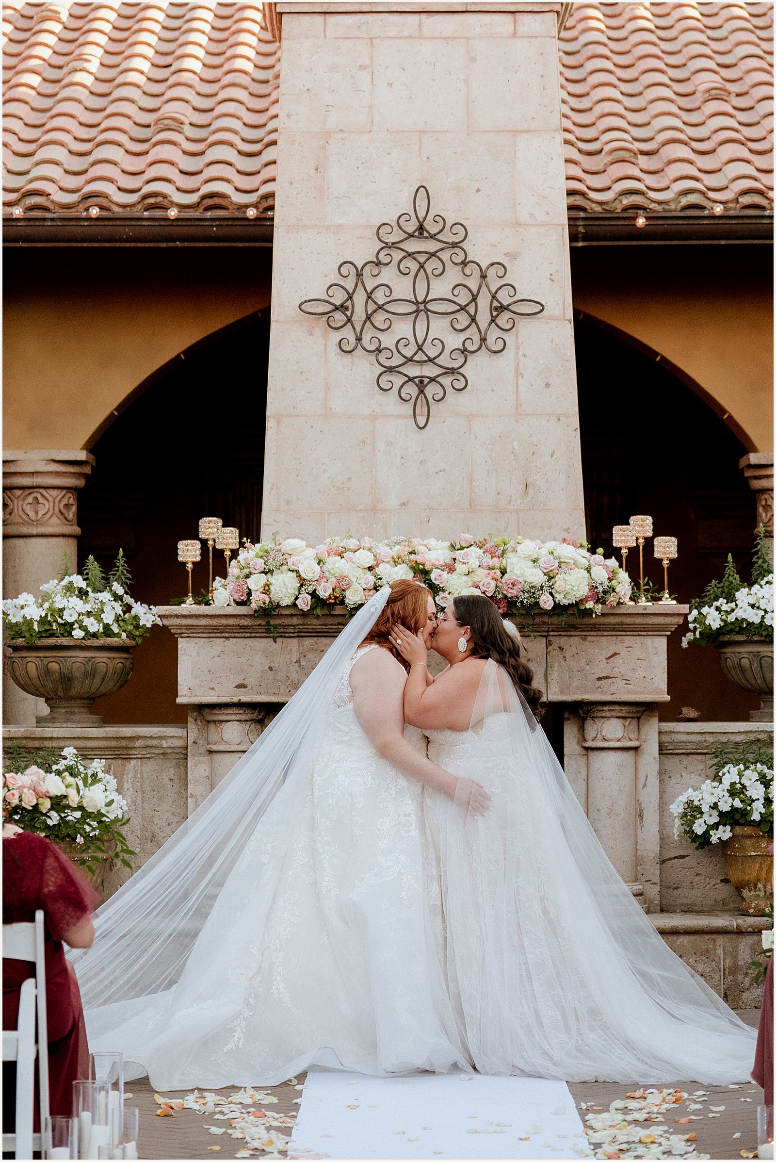 Two brides kiss at an altar at a Villa Siena Arizona wedding.
