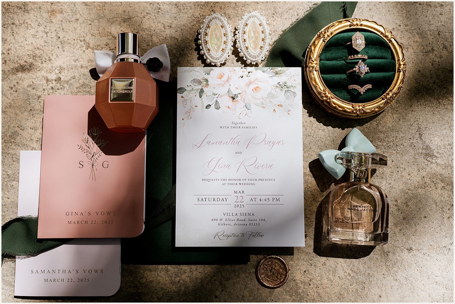 A wedding invitation sits on a table surrounded by jewelry.