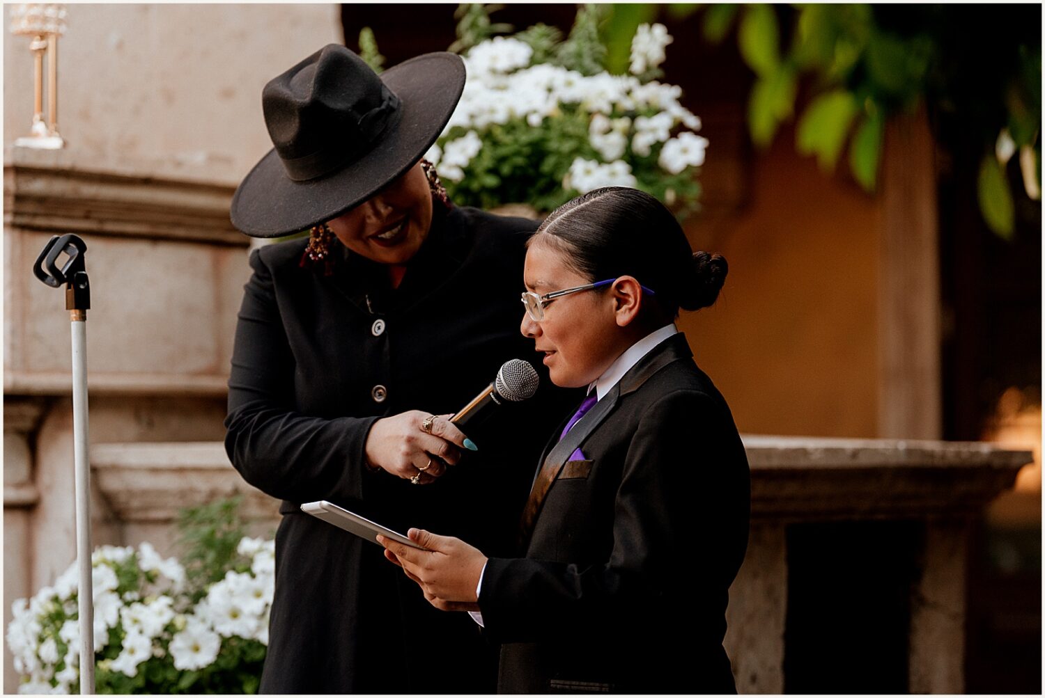 An officiant holds a microphone for a guest to read during a ceremony.