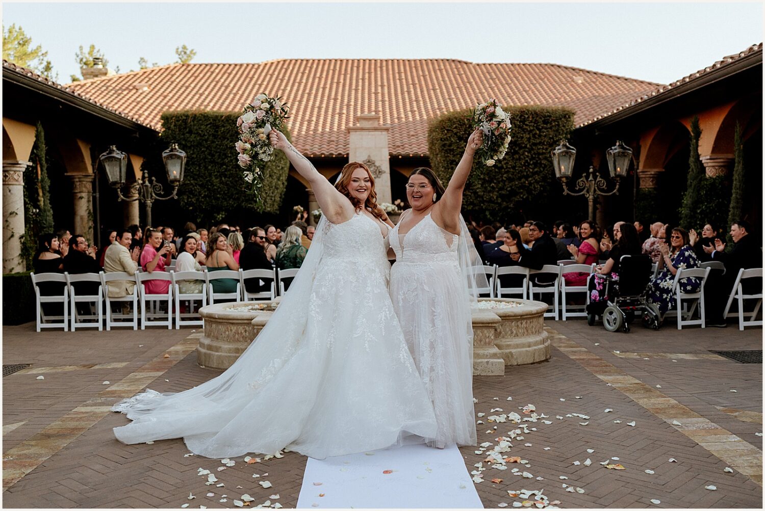 Two brides cheer at the end of their ceremony at an Arizona wedding venue.