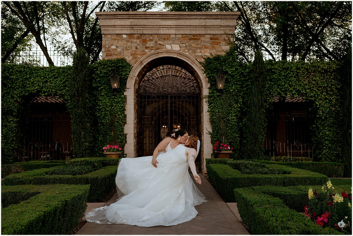 One bride dips another for a kiss in the gardens at Villa Siena Arizona.