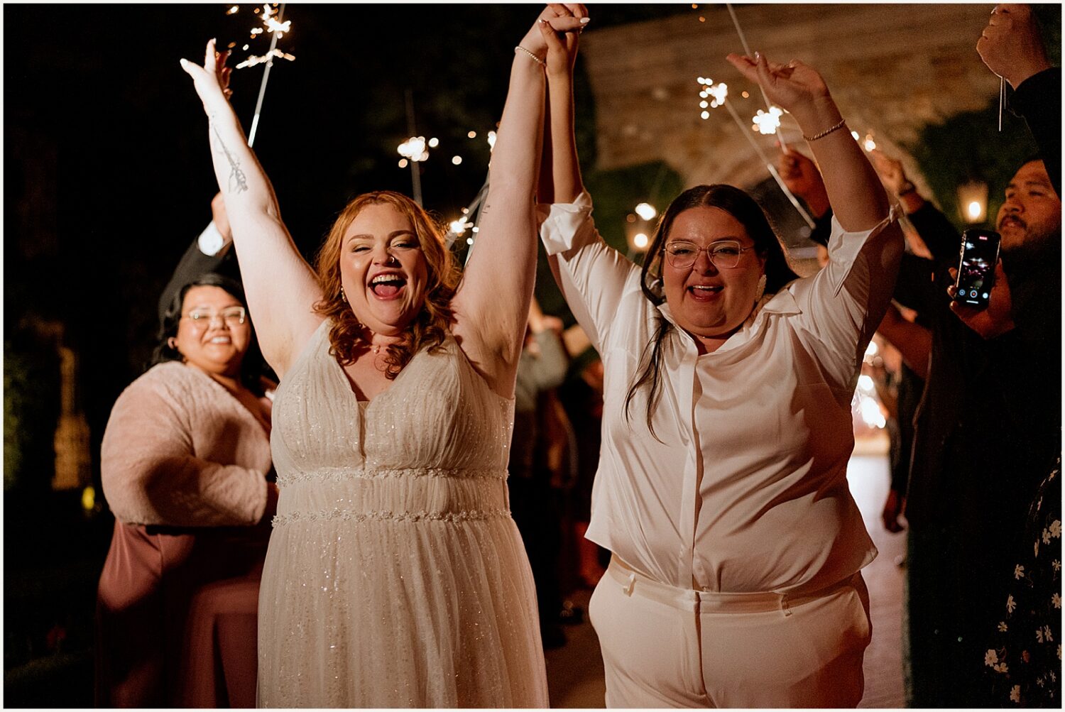 Two brides cheer during a sparkler exit.