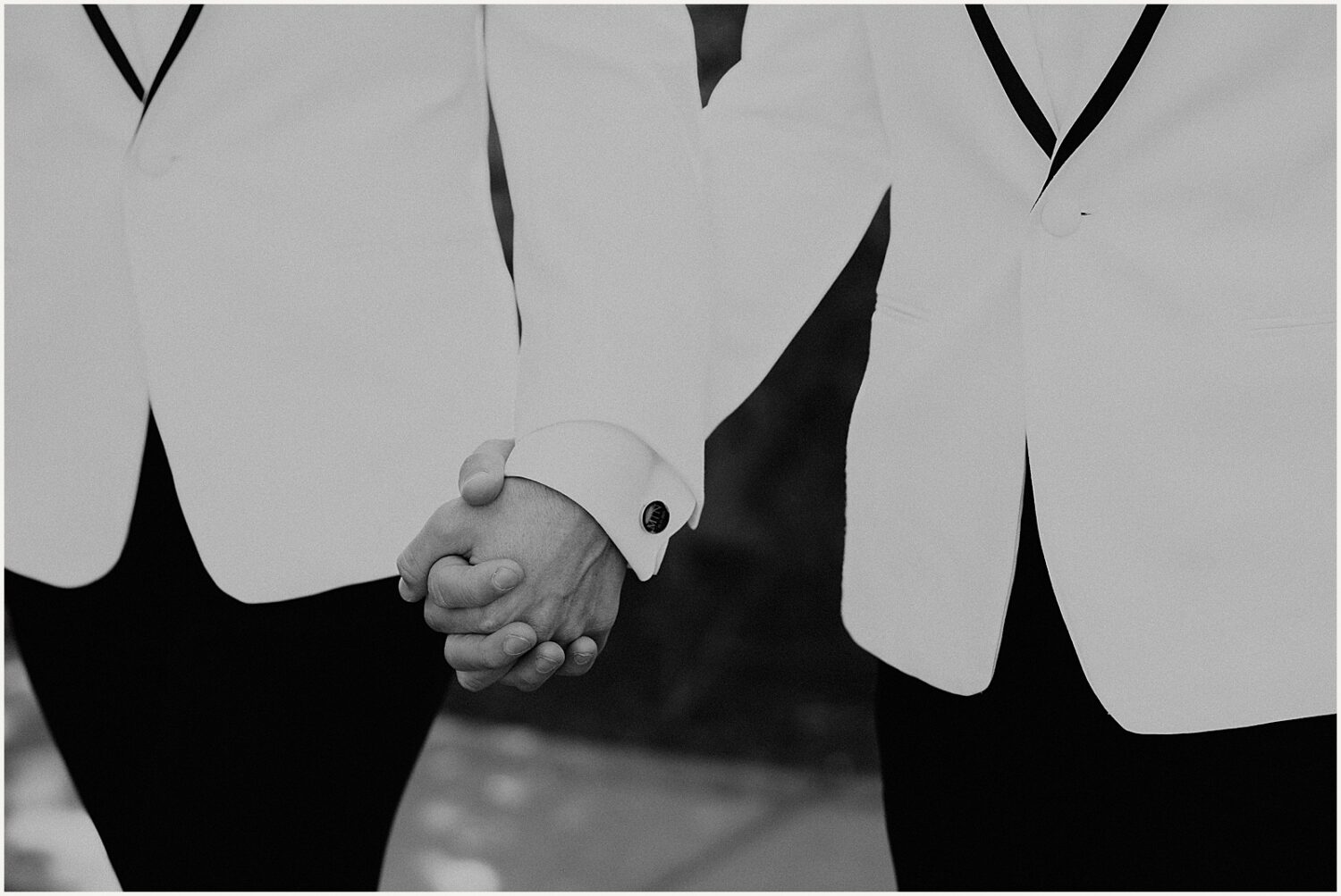 Two grooms hold hands as they walk towards a Phoenix wedding photographer.