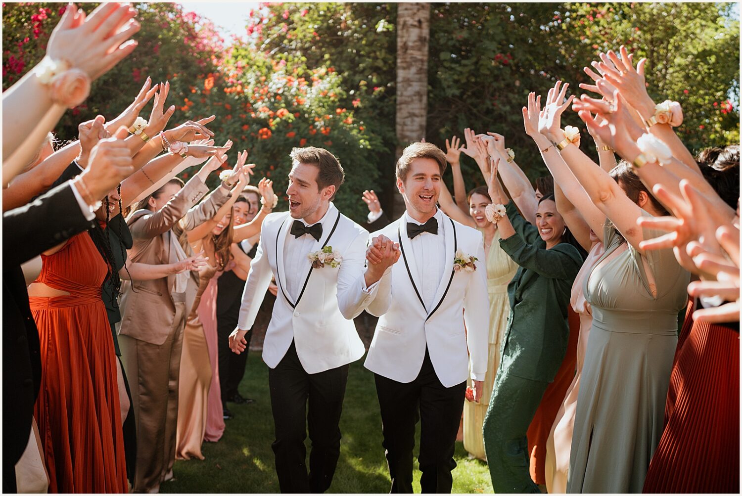 Two grooms run between lines of cheering wedding party members.