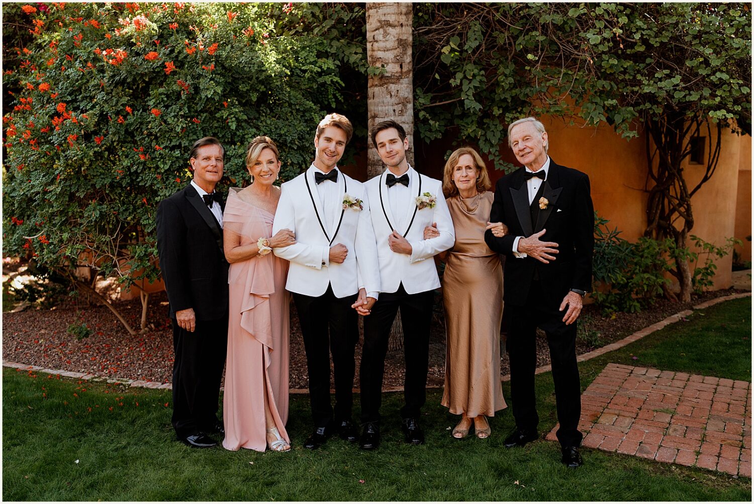 Two grooms pose for a portrait with their parents.