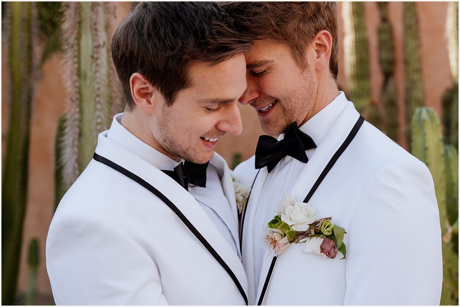 Two grooms cuddle outside a wedding venue.