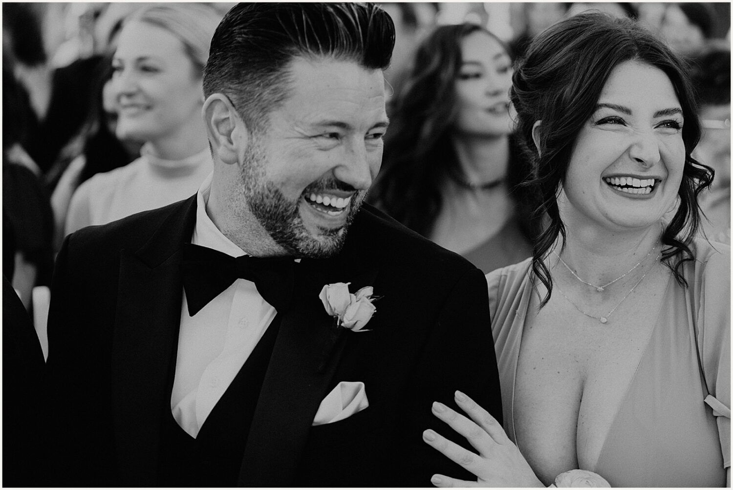 Wedding guests laugh as they wait for a ceremony to start.