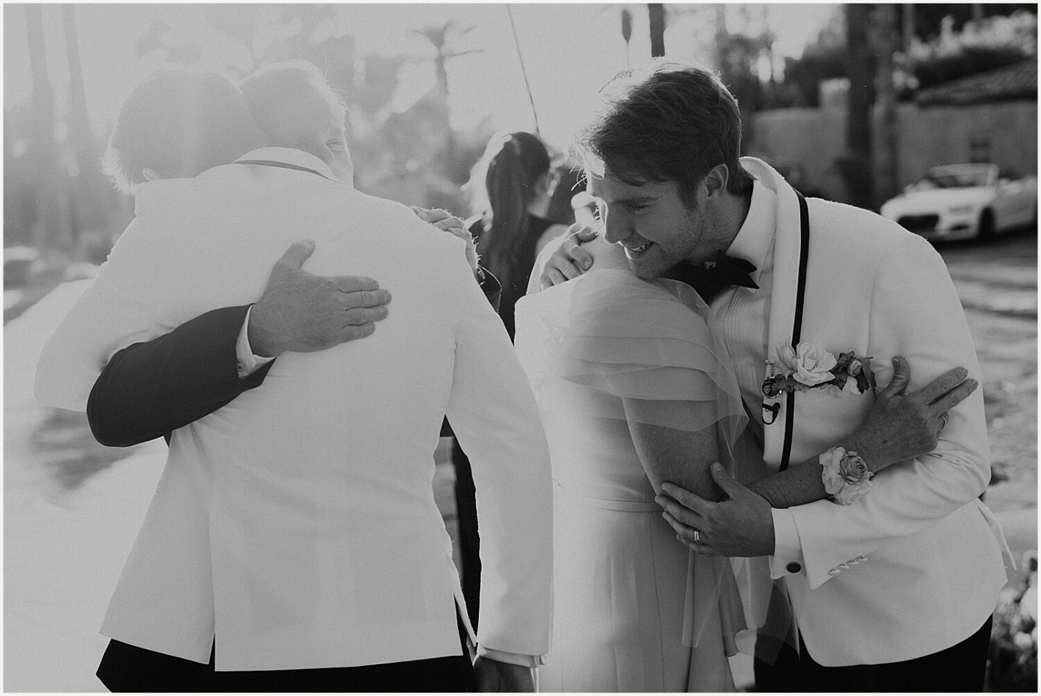 Two grooms hug their parents.
