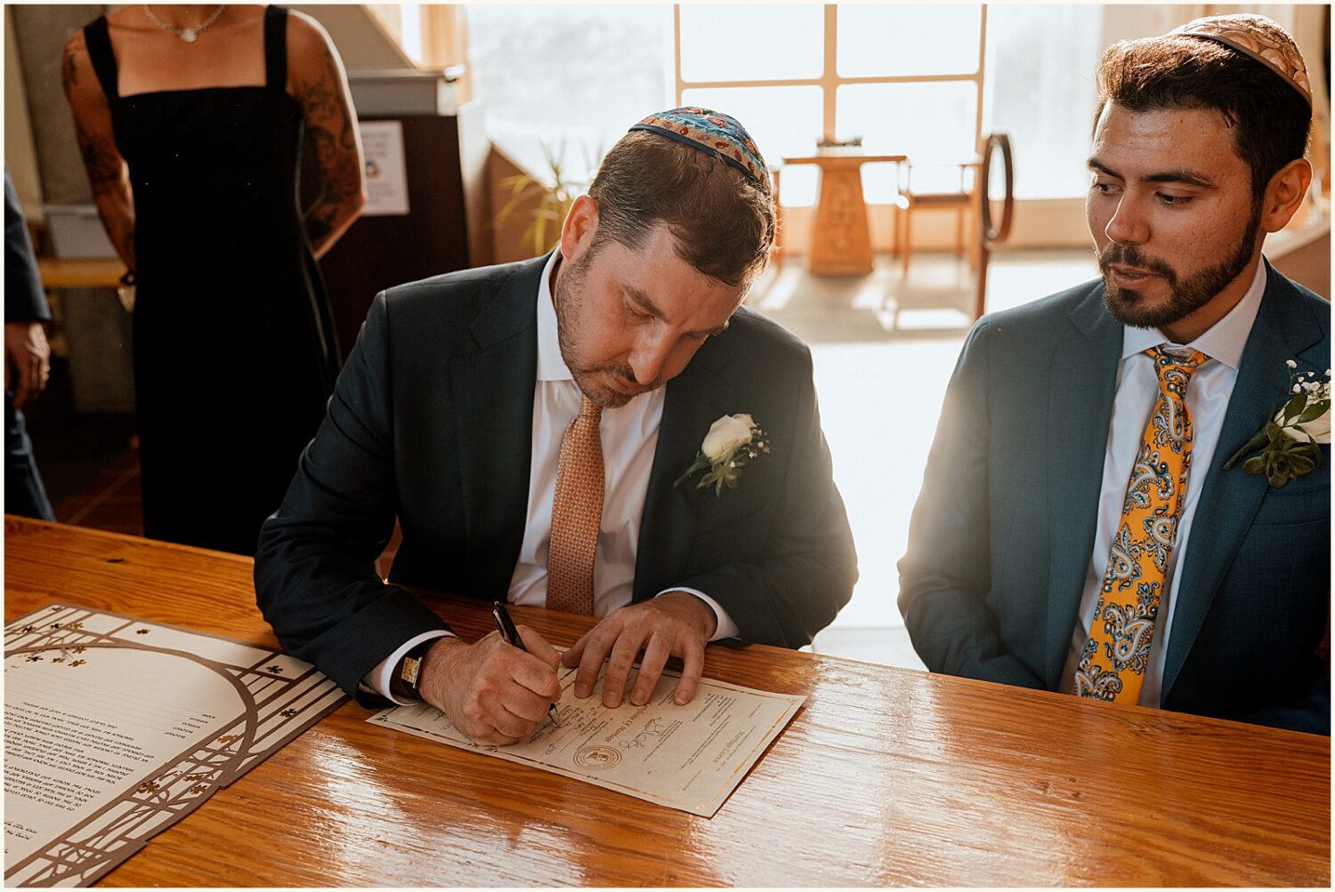 A groom signs a ketubah.