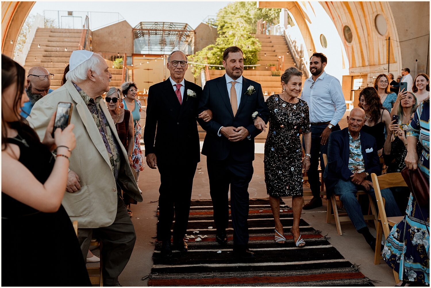 A groom's father walks him up the aisle.