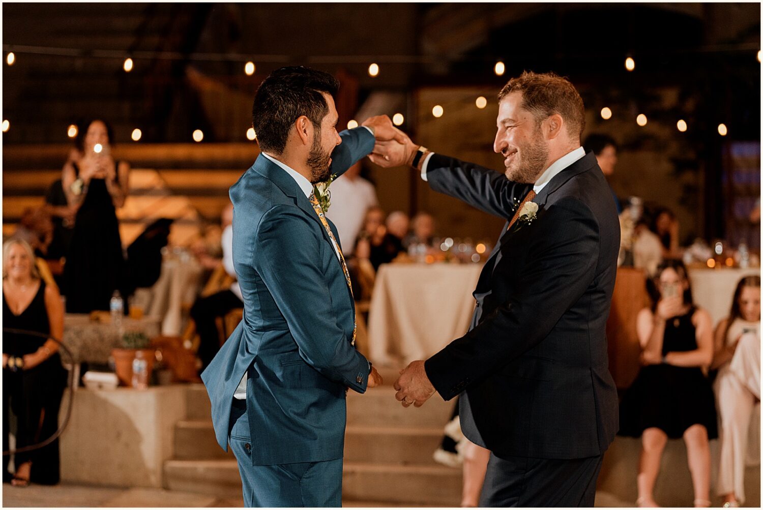 Two grooms dance at a reception.