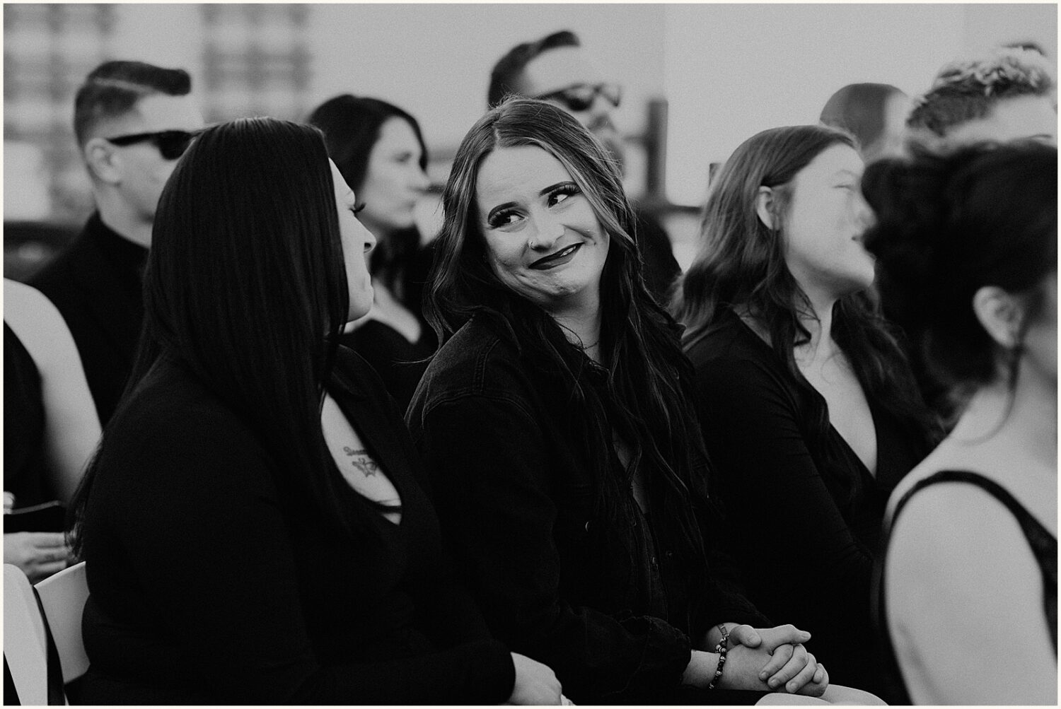 Wedding guests smile at each other during a ceremony.