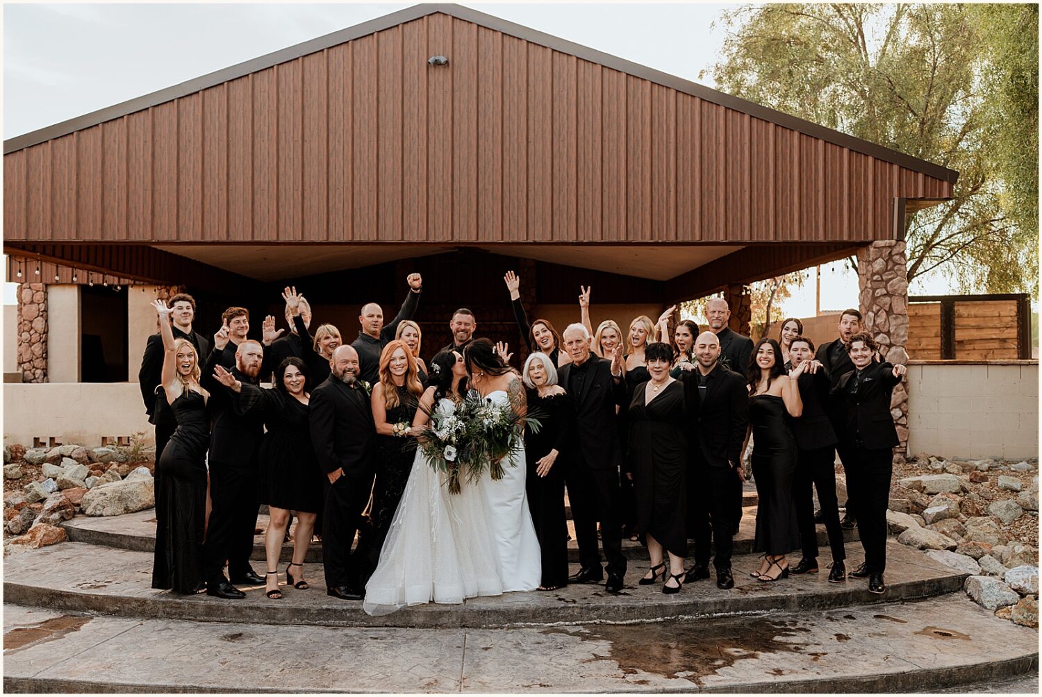 Two brides pose with family members after a wedding.