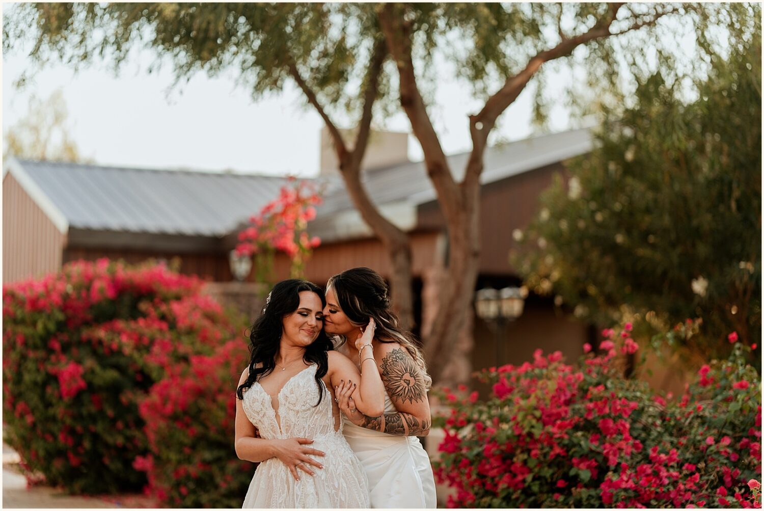 Two brides embrace beneath a tree at an Arizona wedding venue.