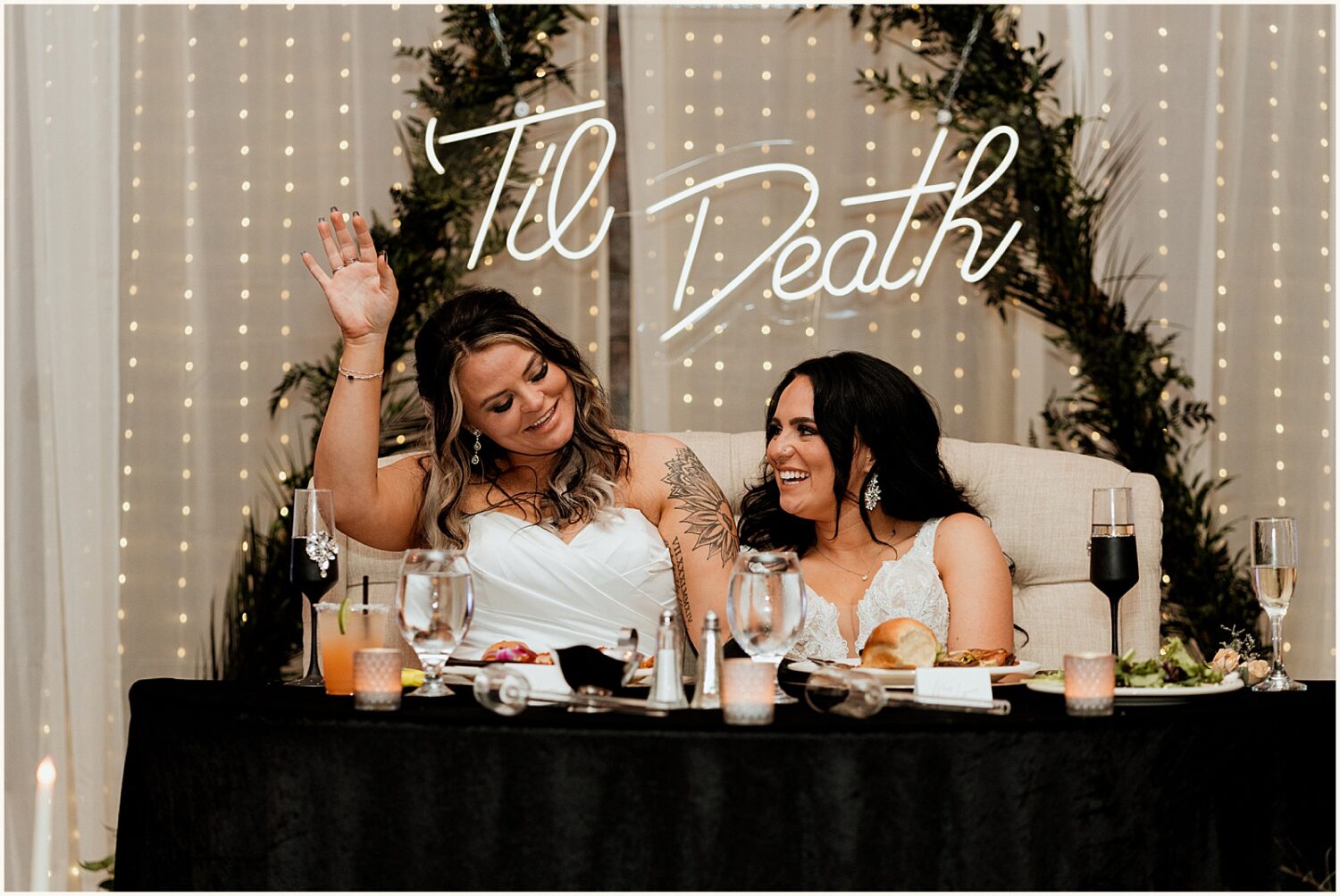 Two brides laugh and clap during a toast.