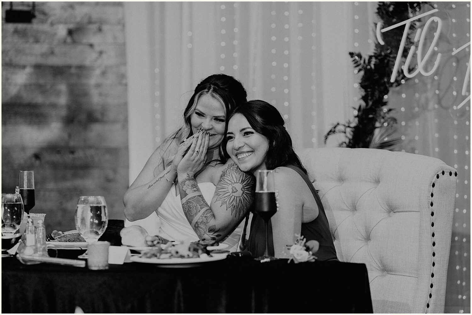 A bride and bridesmaid lean on each other.