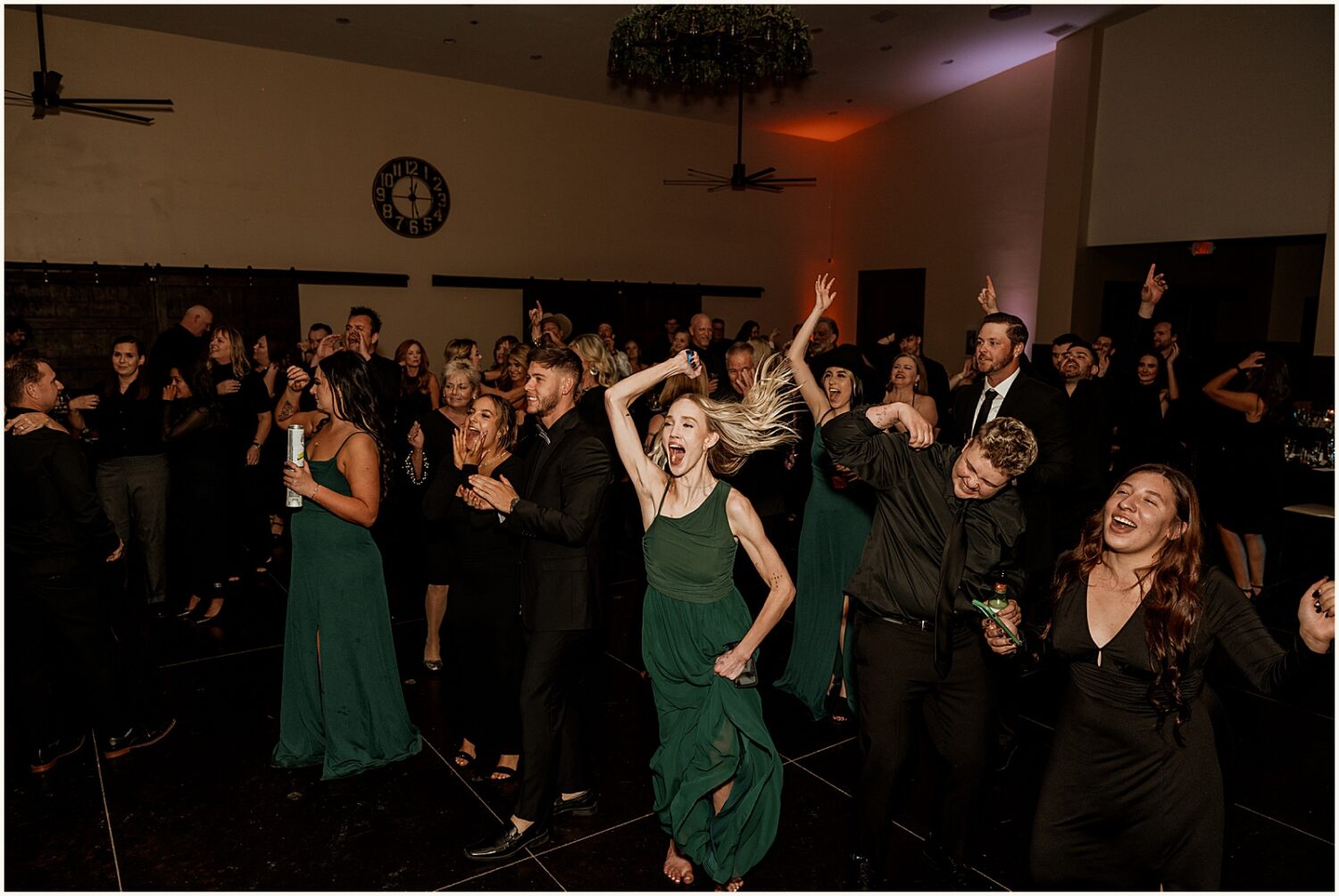 Wedding guests wave their arms on the dance floor.