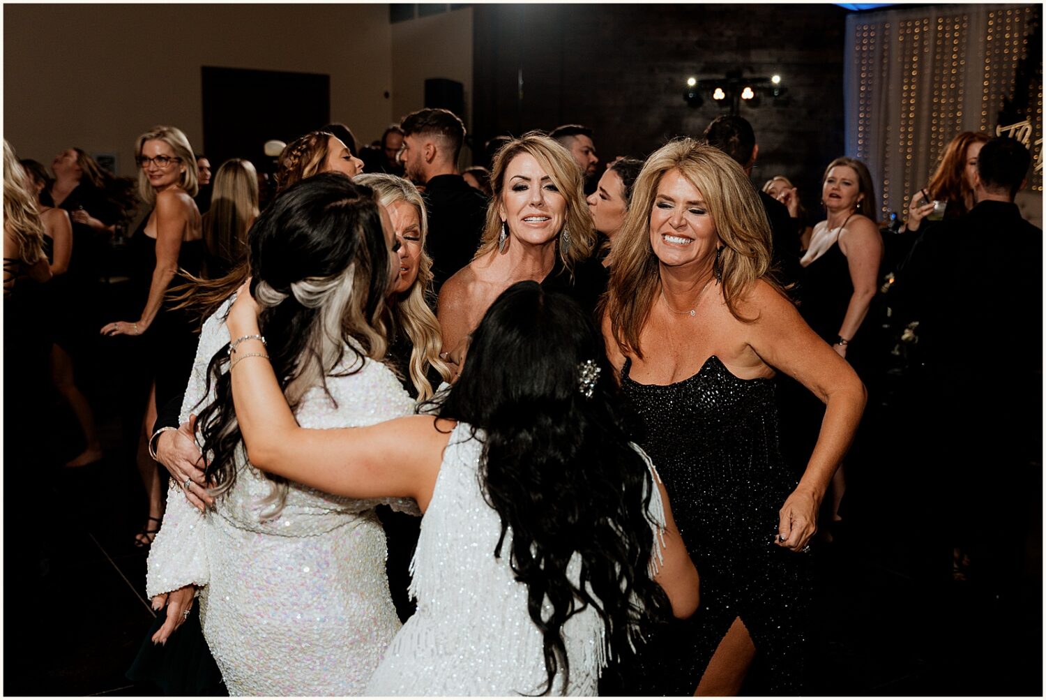 Two brides dance with guests.