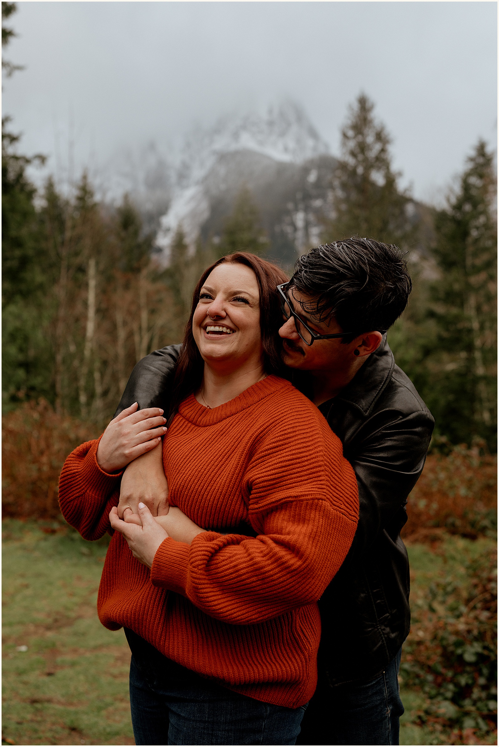 A man and a woman pose for Oregon engagement photos with a mountain in the background.